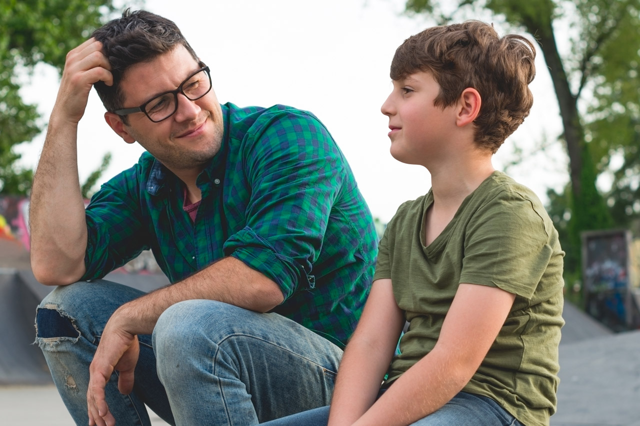 Ein Pädagoge redet mit einem Jungen auf dem Pausenhof.