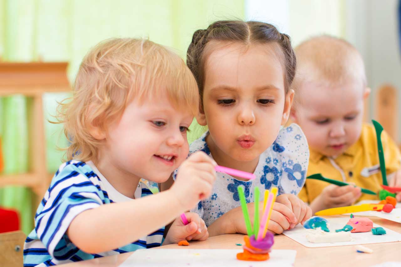 Kindergartenkinder basteln an einem Tisch.
